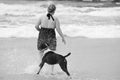 Carefree young woman and her best friend dog playing together in surf beach Royalty Free Stock Photo