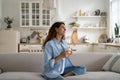 Independent woman dreaming, holding cup of coffee sits on sofa in spacious house enjoying loneliness Royalty Free Stock Photo