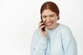 Carefree young woman laughing over phone call, talking on smartphone. Redhead girl chuckle and smile during cellphone