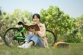 Carefree young woman reading book on green grass at the park with a bicycle Royalty Free Stock Photo