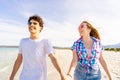 Carefree youth concept: young very happy gen z real couple holding hands tenderly walking on the seashore of tropical beach in Royalty Free Stock Photo