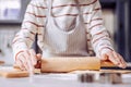 Careful aged woman holding wooden rolling pin while making cookies