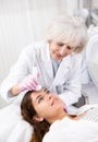 Young woman having face laser therapy procedure by specialist