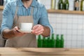 Careful attentive waiter putting a cup of coffee on the wooden table