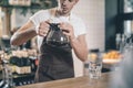 Careful barista looking at the glass coffee jug in his hands