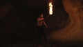 Careful hermit with burning torch in hand walks and looks around in stone cave