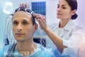 Careful doctor connecting wires on the head of her calm patient