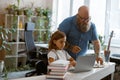 Careful father helps little daughter to prepare to video llesson via laptop at home