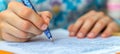 Careful Hand Holding a Patterned Pen Writing on Paper with Many Lines of Fine Text and Copywork Royalty Free Stock Photo