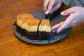Careful hands cutting into a chocolate cake