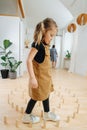 Careful little girl walking on the floor between a spiral from wooden blocks.