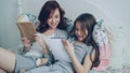 Careful mother helping her little cute daughter with homework for elementary school. Loving mom reading a book and girl Royalty Free Stock Photo