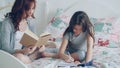 Careful mother helping her little cute daughter with homework for elementary school. Loving mom reading a book and girl Royalty Free Stock Photo