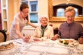Careful nurse sets a table for dinner to patients at nursing home