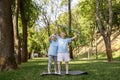 Careful senior woman helps husband to train with bar in green park Royalty Free Stock Photo