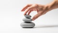 Carefully arranges a stack of three smooth gray stones on a white Royalty Free Stock Photo