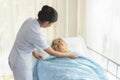 Caregiver in elderly home care giving help grandma on the bed