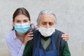 Caregiver with elderly ill woman wearing mask