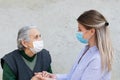 Caregiver with elderly ill woman wearing mask