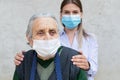 Caregiver with elderly ill woman wearing mask