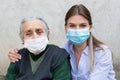 Caregiver with elderly ill woman wearing mask