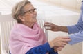 Caregiver giving glass of water to an elegant senior woman