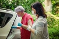 Caregiver helps an elderly client to get into a car to transport for medical appointments.