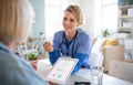 Caregiver or healthcare worker with senior woman patient, measuring blood glucose indoors.