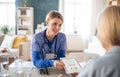 Caregiver or healthcare worker with senior woman patient, measuring blood glucose indoors.