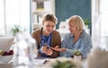 Caregiver or healthcare worker with senior woman patient, measuring blood glucose indoors.