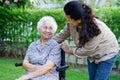 Caregiver help Asian elderly woman disability patient sitting on wheelchair in park, medical concept