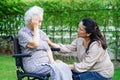 Caregiver help Asian elderly woman disability patient sitting on wheelchair in park, medical concept