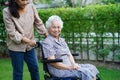 Caregiver help Asian elderly woman disability patient sitting on wheelchair in park, medical concept