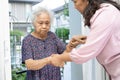 Caregiver help and support Asian senior woman while walking, stepping up to the door of the house Royalty Free Stock Photo