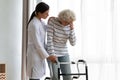 Caregiver helping disabled older woman standing with walker, feeling unwell Royalty Free Stock Photo