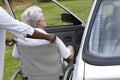 Caregiver helping a disabled senior lady to get inside of her car