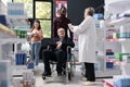 Caregiver helping senior customer in wheelchair with health care shopping in pharmacy