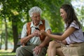 Caregiver helping senior diabetic man check his glucose data on smartphone outdoors, in park. Royalty Free Stock Photo