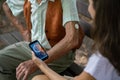 Caregiver helping senior diabetic man check his glucose data on smartphone outdoors, in park. Royalty Free Stock Photo