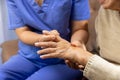 Caregiver massaging finger of elderly woman in painful swollen gout