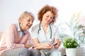 Caregiver measuring blood sugar of senior woman at home. Kind carer measuring the blood sugar of a happy elderly woman in bed in