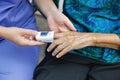 Caregiver monitoring oxygen saturation at fingertip of elderly