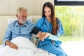 Caregiver nurse using blood pressure monitor to Senior patient sit on Bed. Nurse helping senior Man. Royalty Free Stock Photo