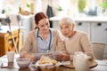 Caregiver reading morning news for retired woman Royalty Free Stock Photo