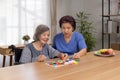 Caregiver and senior woman playing wooden shape puzzles game for dementia prevention