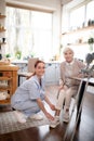 Caregiver smiling while helping aged woman to lace shoes Royalty Free Stock Photo