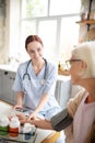 Caregiver smiling while measuring pressure for aged woman