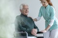 Caregiver supporting happy disabled senior man in a wheelchair i