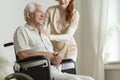 Caregiver supporting sick elderly man in the wheelchair during s