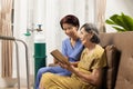 Caregiver takecare elderly woman while wearing oxygen nasal cannula at home